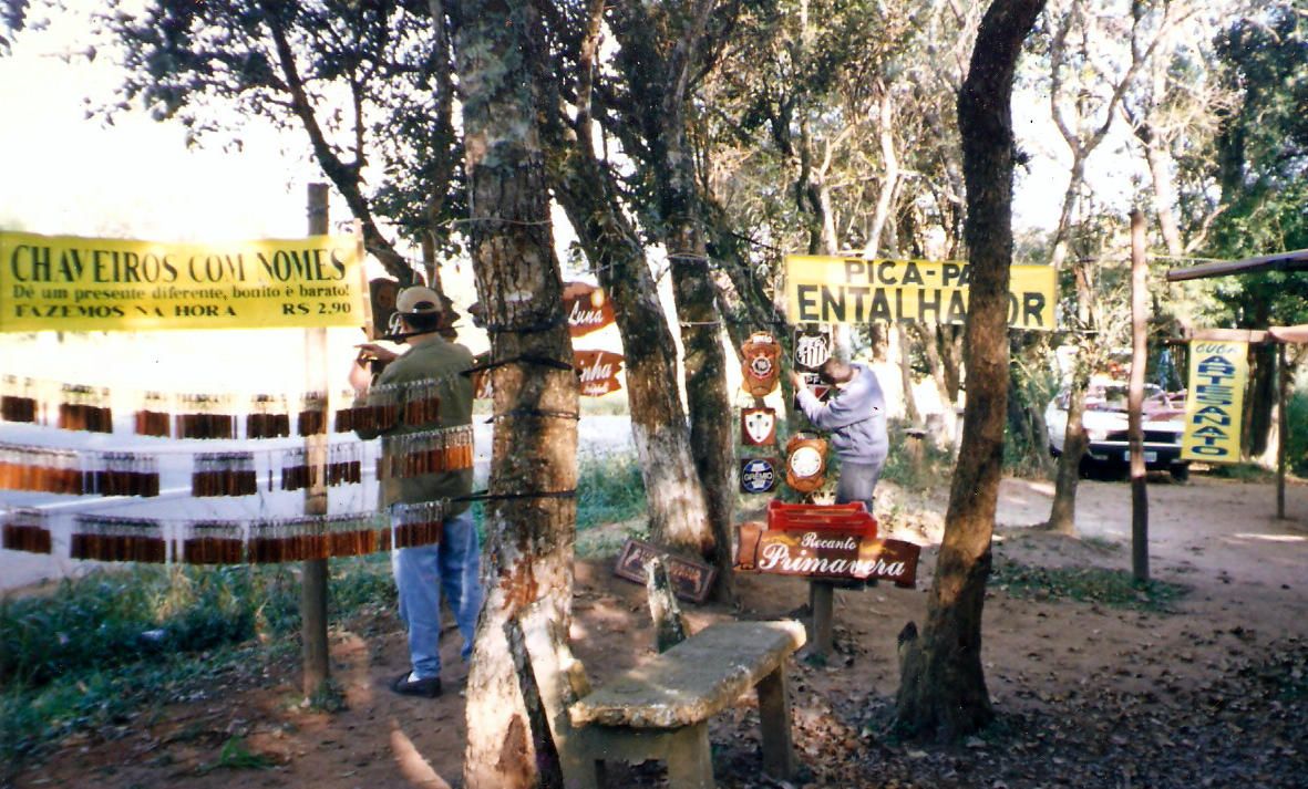Barraca da Pica-pau Entalhes na feirinha de Ibiúna, abril de 1999. Peças expostas entre árvores com placa 'Pica-Pau Entalhador'