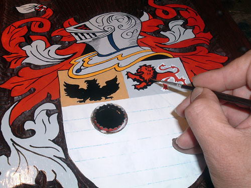 Mão pintando detalhes de um brasão de família
